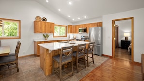 Una cocina moderna con armarios de madera, una isla grande con taburetes de bar, un microondas y un refrigerador.