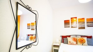 Een hotelkamer met een bed, nachtkastje, spiegel en wanddecoratie.
