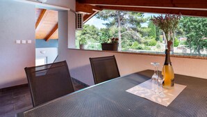 An outdoor dining area with a table, chairs, a bottle of champagne, and a vase of flowers. - Beach front home in Peroj (Peroj)