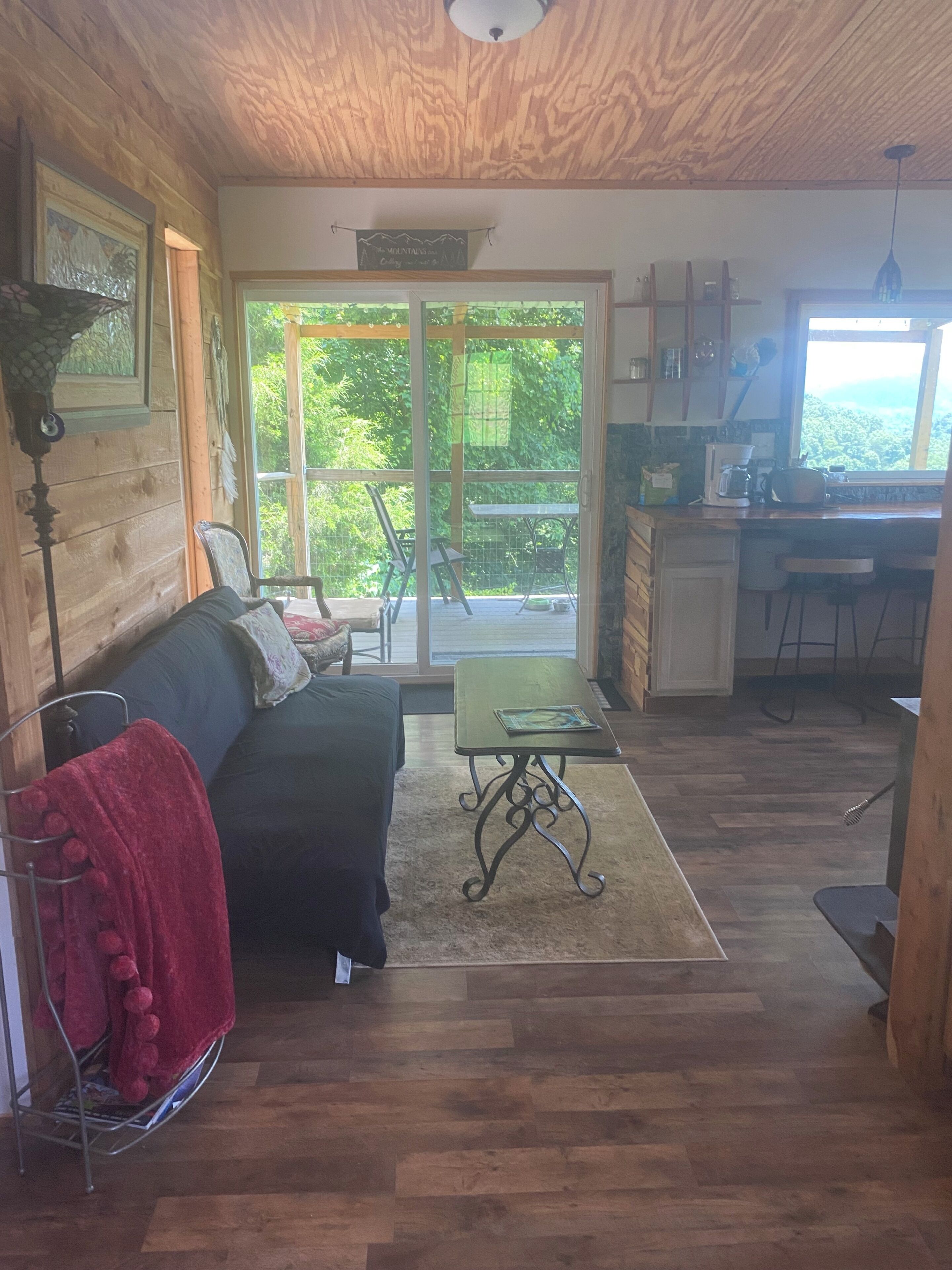 L’intérieur chaleureux d’un chalet avec un plafond en bois, un canapé, une table à manger et un coin cuisine.