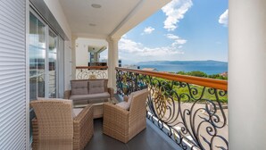 A balcony with wicker furniture, a view of the sea, and a distant mountain range. - Lovely home in Crikvenica (Crikvenica)