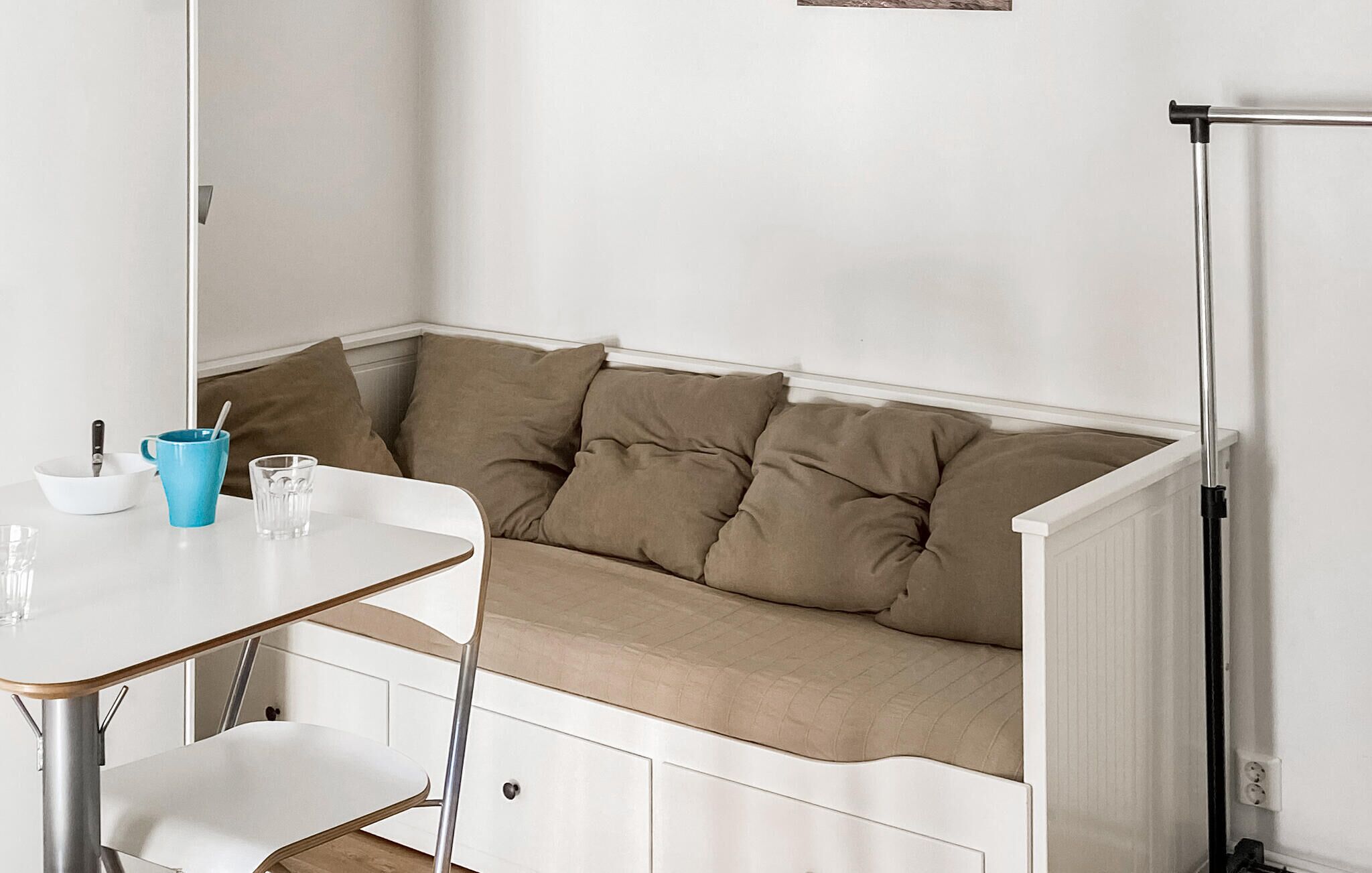 Un coin salon avec une table et des chaises blanches, une tasse bleue et un verre.