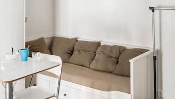 Een zithoek met een witte tafel en stoelen, een blauwe mok en een glas.