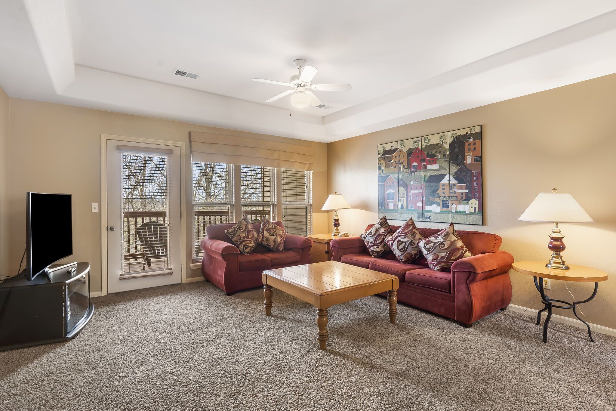 A living room with a red sofa, a wooden coffee table, a TV, and two lamps.