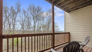 A wooden deck with a railing, two Adirondack chairs, and a view of leafless trees. - Combined Condo & Suite with Lock-off Access at StoneBridge (Reeds Spring)
