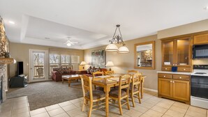 A spacious living room with a dining area, a kitchen with wooden cabinets, and a large window with blinds. - Combined Condo & Suite with Lock-off Access at StoneBridge (Reeds Spring)