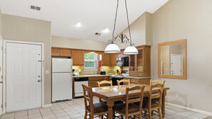 A kitchen with a dining table, chairs, and a hanging light fixture. - Golf Condo with Fireplace & Jetted Tub at StoneBridge Village (Reeds Spring)