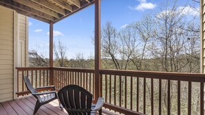 A wooden deck with two chairs and a view of trees and hills. - Perfect for a Couple! Condo at StoneBridge Village Resort (Reeds Spring)