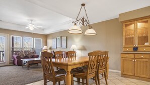 A dining area with a wooden table and chairs, a chandelier, and a kitchen with wooden cabinets. - Perfect for a Couple! Condo at StoneBridge Village Resort (Reeds Spring)