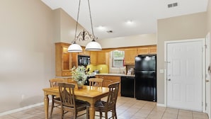 A kitchen with wooden cabinets, a black refrigerator, and a dining table with chairs.