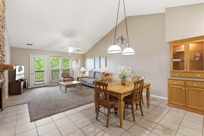 Een ruime woonkamer met een eettafel, stoelen, een bank en een open haard.