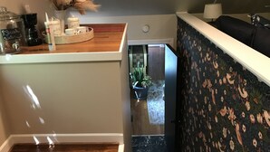 Una zona de cocina con cafetera, un tarro etiquetado como "agua fresca" y un jarrón decorativo con plantas secas.