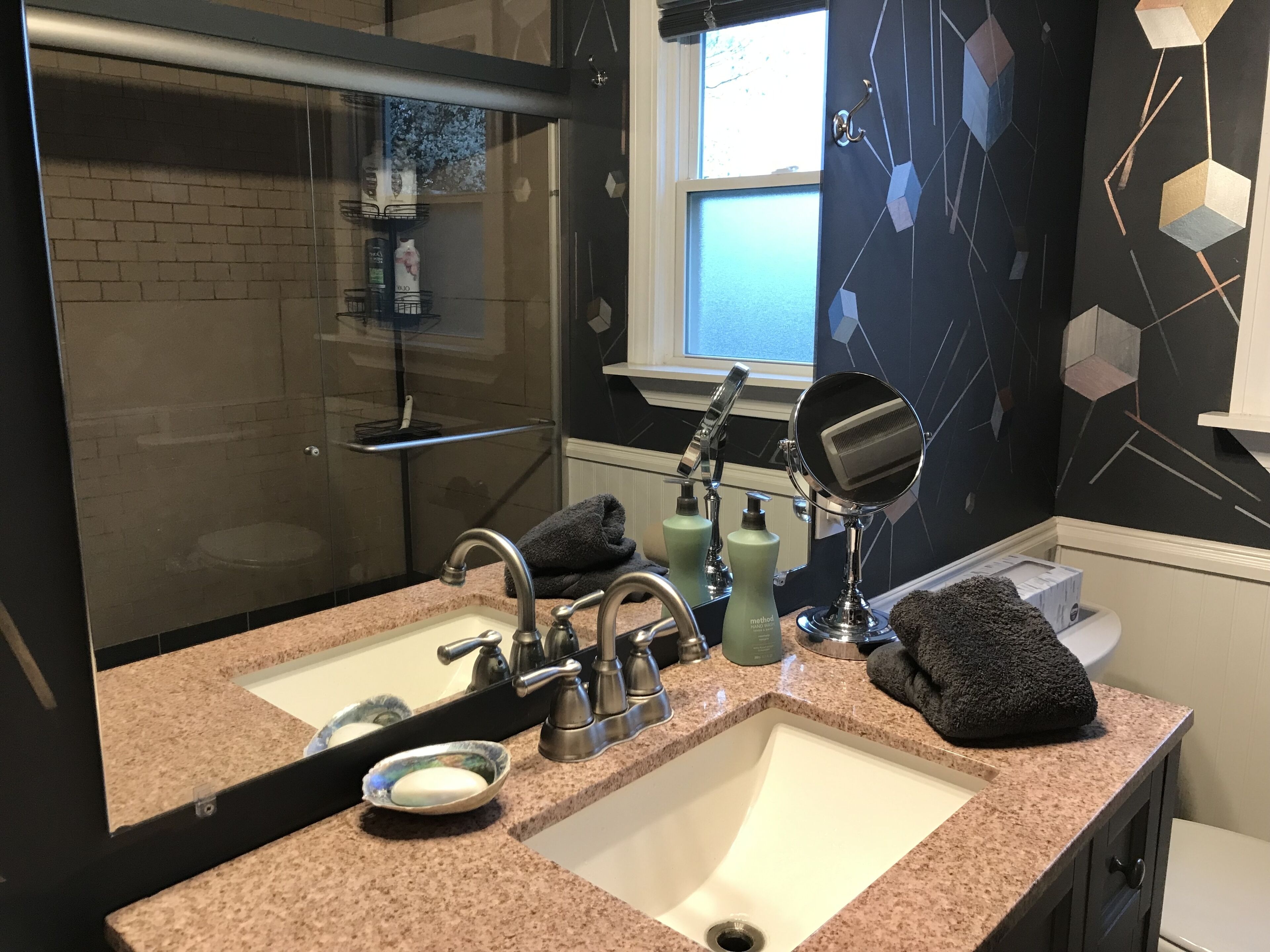 Une salle de bain avec deux lavabos, un grand miroir et une fenêtre.