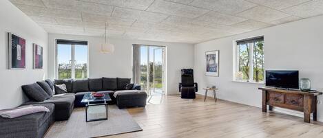 Een moderne woonkamer met een hoekbank, een flatscreen televisie en een open haard.