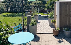 A patio with a blue table and chairs, surrounded by potted plants and a stone pathway. - Beautiful apartment in Bohus-Malmön (Bohus-Malmön)
