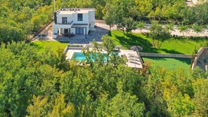 Ein modernes, zweistöckiges Haus mit Swimmingpool, umgeben von üppiger Vegetation.