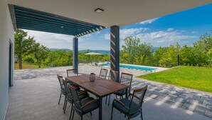 Eine Außenpatio mit Pool, umgeben von üppiger, grüner Landschaft und Bergen im Hintergrund.