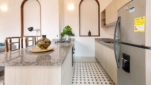 A kitchen with a granite countertop, a stainless steel refrigerator, and a tiled floor. - 2CM-J1 APARTAMENTO EN GETSEMANI CON WIFI (Cartagena)