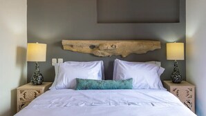 A neatly made bed with white linens, a teal accent pillow, and two bedside lamps with floral vases. - 2CM-J1 APARTAMENTO EN GETSEMANI CON WIFI (Cartagena)