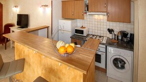 A compact kitchen with wooden cabinets, a microwave, a gas stove, and a washing machine. - 2 bedroom cozy home in Rousset les Vignes (Rousset les Vignes)