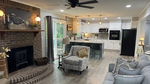 A spacious living room with a fireplace, a dining area, and a kitchen with white cabinets and a black refrigerator. - Renovated!  Peaceful farm setting.  Close to TTU, town and Cummins Falls. (Cookeville)