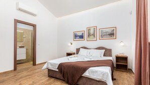 Ein Schlafzimmer mit einem Bett, Nachttischen, einem Spiegel und gerahmten Bildern an der Wand.