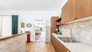 Eine schmale Küche mit Holzausstattung, einer Ziegelwand und Blick auf einen Außenbereich zum Sitzen.