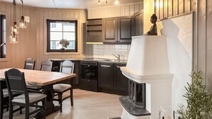 Une cuisine moderne avec des meubles de couleur sombre, un fourneau blanc et un coin repas comprenant des chaises et une table en bois.