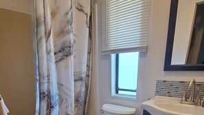 Un baño con inodoro, lavamanos y cortina de ducha.
