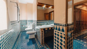 A bathroom with a checkered tile floor and walls, a sink, a toilet, and a shower area. - Palace Jena Hotel & Spa (Marrakech)