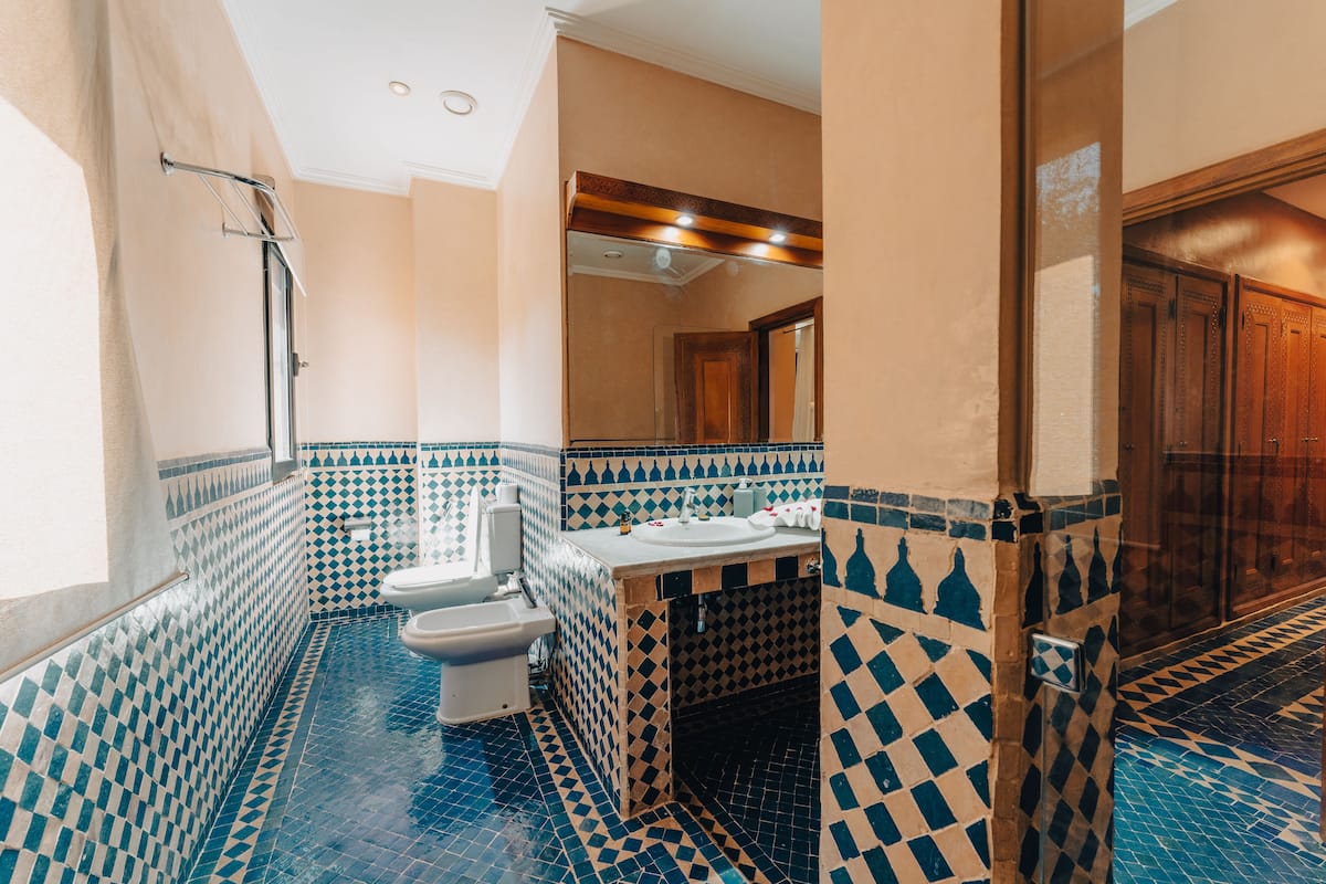 A bathroom with a checkered tile floor and walls, a sink, a toilet, and a shower area.