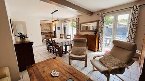 Un salon spacieux comprenant un coin repas, une cuisine et un balcon agrémenté de rideaux.