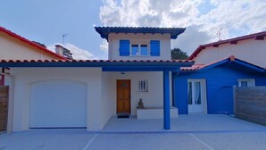 Une maison à deux étages avec un garage, une porte d’entrée et une petite statue.