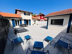 A courtyard with outdoor seating, a covered area, and buildings with red-tiled roofs.