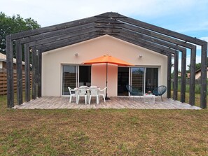 Relax on the patio with a glass door leading to the interior space, surrounded by a grassy lawn and a wooden fence.