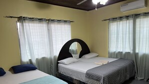 Una habitación con dos camas, cada una con un diseño de cabecera diferente, y un ventilador de techo.