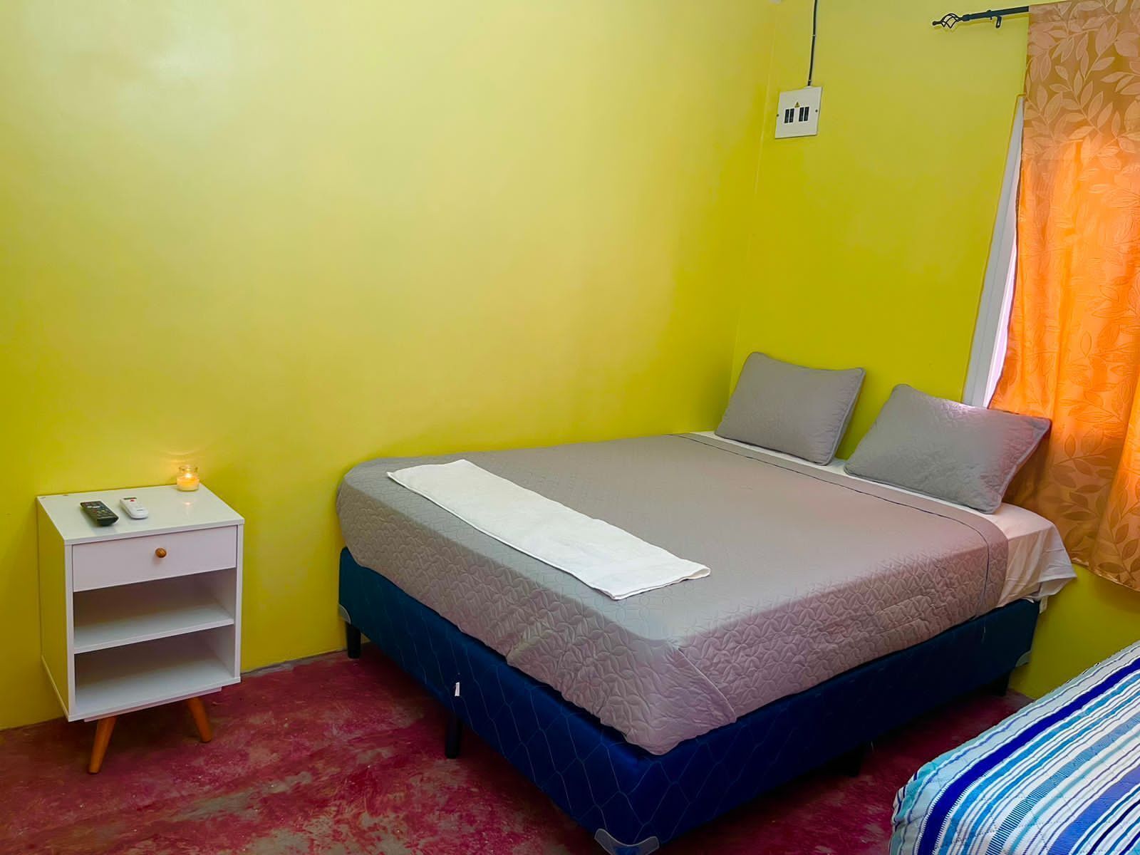A bedroom with a bed, a nightstand, and a power outlet on the wall.