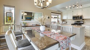 A spacious kitchen with a central island, white cabinetry, and modern appliances.