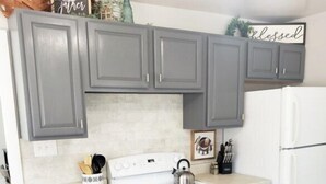 A kitchen with grey cabinets, a white stove, and a white refrigerator.