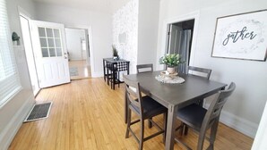 A dining area with a dark wooden table and chairs, a ceiling fan, and a framed 'gather' sign on the wall.