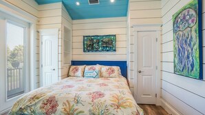 A bedroom with a bed, a ceiling with a blue accent, a wall-mounted painting, and a window with blinds. - Pineapple Cay: 2.5 Blocks to Beach! Pool & Spa by Anna Maria Life Vacation Rentals (Holmes Beach)