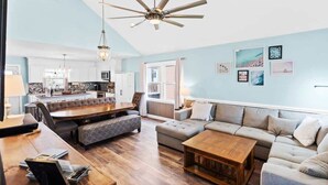 A spacious living area with a dining table, sofa, and a ceiling fan.