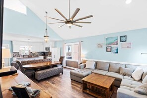 A spacious living area with a dining table, sofa, and a ceiling fan.
