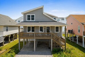 A two-story residential building with a covered porch and a small staircase leading to the upper level.