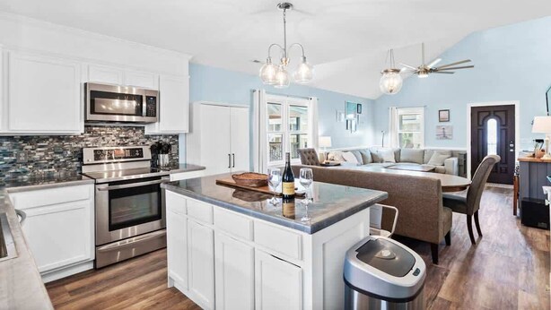 A modern kitchen with built-in appliances, a central island, and a dining area with a sofa.
