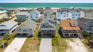 A coastal residential area with houses, a beach, and a clear sky.