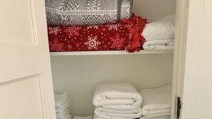 Een kast met planken volgevouwen handdoeken en gestreepte dekens.