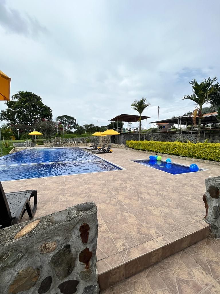 A swimming pool area with two pools, a stone wall, and a tiled deck.