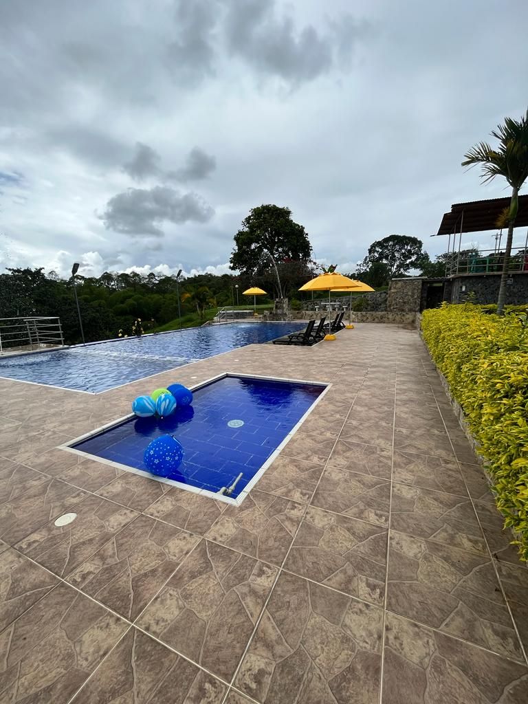 A swimming pool with a tiled deck, two yellow umbrellas, and a small pool area with blue balls.
