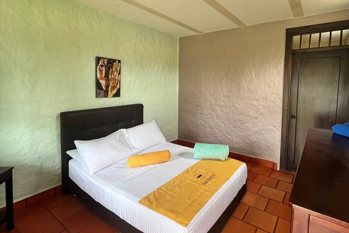 A single bed with white linens, a headboard, and a yellow towel.